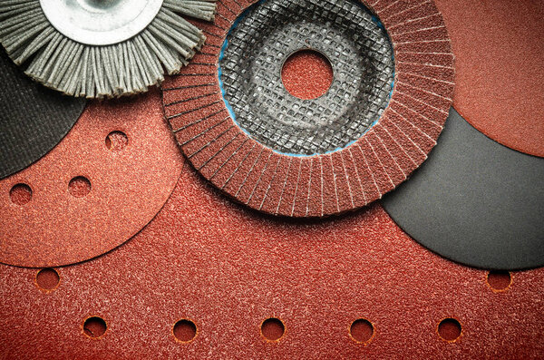 Set of abrasive tools and grinding discs on the background of sandpaper. Essential tools for master builder.