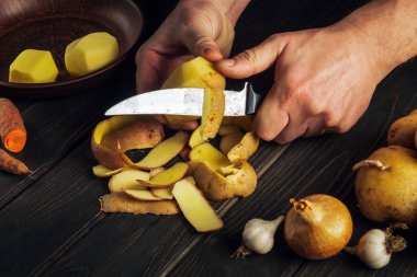 Şef ulusal bir yemek ya da patates kızartması hazırlamak için çiğ patatesleri bıçakla soyuyor. Lezzetli sebze kahvaltısı ya da öğle yemeği