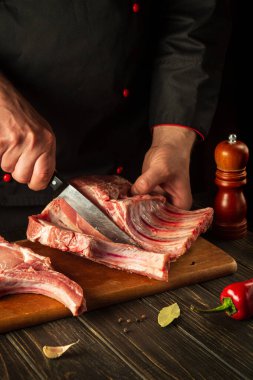 Şef pişirmeden önce bir kesme tahtasıyla çiğ kaburga keser. Avrupa mutfağı. Mutfakta lezzetli yemekler pişirmek.