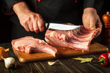 Ateş için, çiğ kaburgalar küçük parçalara ayrılmalıdır. Mutfakta bıçağı olan bir şefin elleri. Bir restoran için lezzetli yemekler pişirmek.