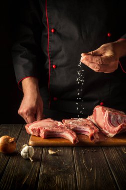 Profesyonel şef çiğ kaburga ve tuz serpiyor. Otel için lezzetli yemekler pişirme fikri..