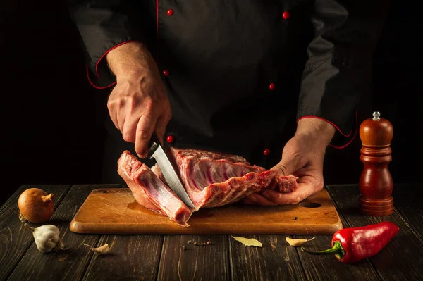 Şef barbekü yapmadan önce çiğ pirzola keser. Avrupa mutfağı. Otel mutfağında lezzetli yemekler pişirmek.