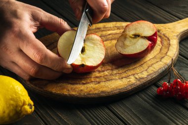 Aşçı komposto veya meyve suyu yapmak için elmaları kesme tahtasıyla keser. Bir dizi vitamin için elma diyeti. Mutfak masasında çalışma ortamı.
