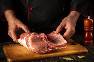 Aşçı bir parça çiğ eti kemikle birlikte tutuyor. Kasap ellerinde domuz pirzolası. Asya mutfağı