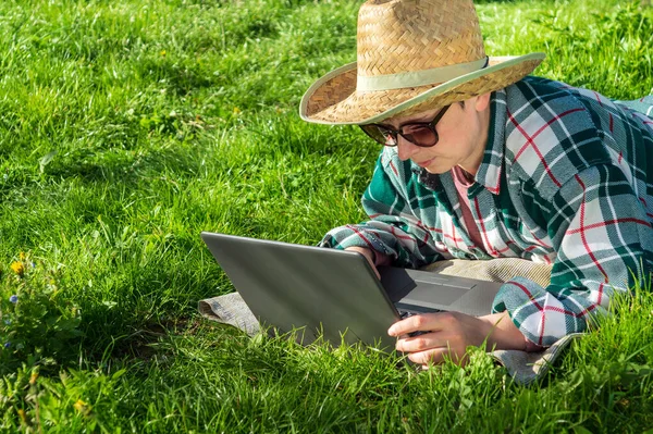 眼鏡をかけた45歳の女性は 屋外でフリーランスとして活動しています 緑の芝生を背景に 晴れた日に公園の自然界のノートパソコンで休む — ストック写真