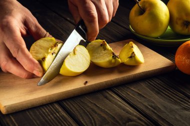 Bıçaklı bir aşçının elleri kesme tahtasındaki taze elmaları kesiyor. Elma diyeti ya da oruç tutma fikri