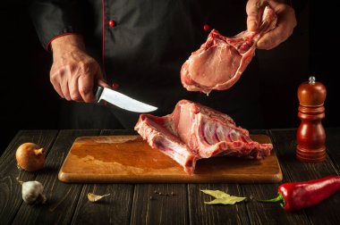 Şef pişirmeden önce bir kesme tahtasıyla çiğ kaburga keser. Avrupa mutfağı. Mutfakta lezzetli yemekler pişirmek.