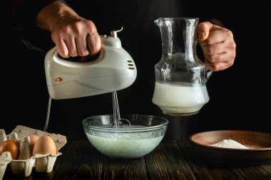 Profesyonel şef lezzetli bir kahvaltı hazırlamak ya da yumurta ve sütle öğle yemeği hazırlamak için el yapımı elektrikli mikser kullanır. Restoran ya da otel için menü fikri