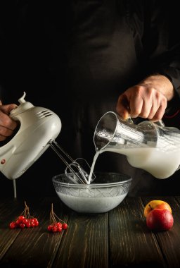 Mutfaktaki şefin eliyle ferahlatıcı bir içecek hazırlıyorum. Meyveli milkshake. Elektrikli karıştırıcı kullanıyor..