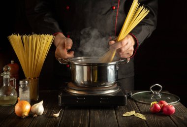 Şef mutfakta bir tencerede spagetti pişiriyor. Moleküler gastronomi. Reklam için boş alan