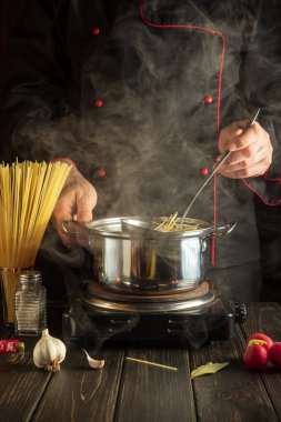 Şef mutfakta bir tencerede spagetti çorbası hazırlıyor. Lezzetli bir yemek hazırlamak için bir otel fikri