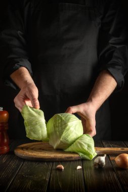 Profesyonel şef taze sebzeli mutfak masasında salata için bıçakla taze lahana keser. Aşçılık ve restoran veya otel konsepti