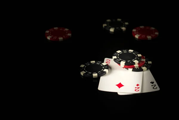 Playing cards on a black table with a winning combination one pair in game poker and chips in the background.