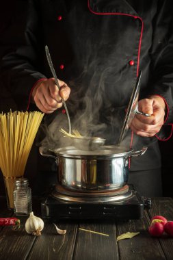 Şef mutfakta kaynayan bir tencerede spagetti pişirir. Otel veya restoran menüsü veya tarifi