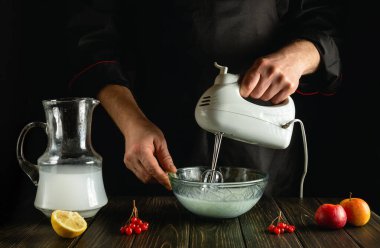 Şef, el yapımı elektrikli mikser kullanarak ananas suyu ve meyveli bir kokteyl hazırlıyor. Mutfaktaki şefin eliyle ferahlatıcı içecek.