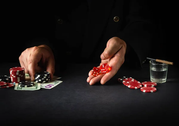 Dice game in a poker club. Player holding two dice before rolling on dark table in casino.