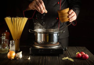 Şef mutfakta bir tavada İtalyan spagettisi pişirir. Büyük mutfak..