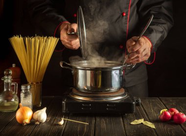 Şef akşam yemeğini hazırlarken spagettiyle çorba pişiriyor. Mutfakta yemek pişirirken