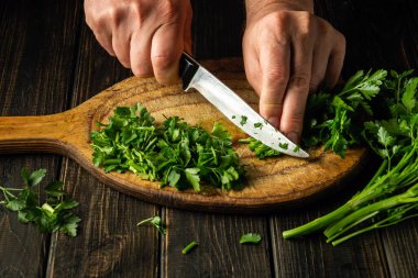 Vejetaryen yemeği hazırlamak için kesme tahtasına yeşil maydanoz yaprakları kesen şeflerin yakın çekimi. Köylü yemekleri..