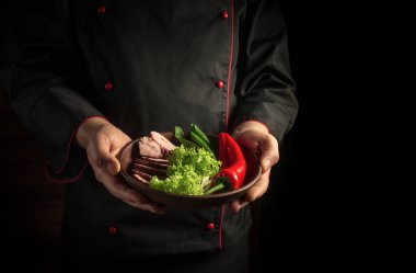 Şef taze sebze salatası ve biberli ızgara biftek servis ediyor. Restoran veya otel menüsü