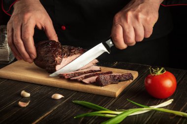 Tecrübeli aşçı bifteği ahşap bir masada bıçakla keser. Yemek pişirme süreci konsepti