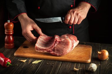 Barbekü yapmadan önce domuz pirzolası kestiği için mutfakta bıçaklı bir şefin elleri. Restoran ya da otel için lezzetli yemekler pişirmek.
