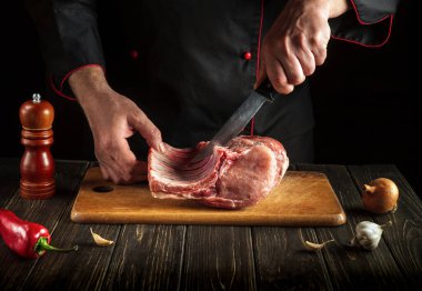 Mutfakta bıçakla domuz pirzolası kesen bir kasap elleri. Bir otel ya da restoran için lezzetli yemekler pişirmek.