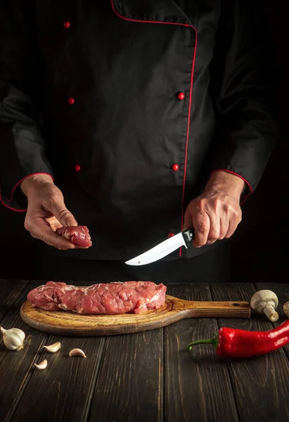 Experienced chef cuts raw veal meat on a cutting board before barbecue. Cooking delicious food for lunch in the kitchen