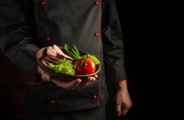 Şef yemeği sebzeli bir tabak kızarmış biftekle sunar. Reklam için boş alan