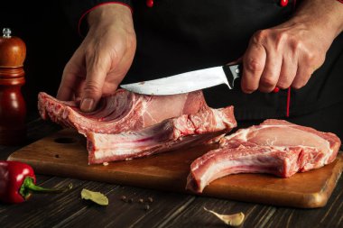 Şef pişirmeden önce çiğ pirzola keser. Mutfakta lezzetli yemekler pişirmek..