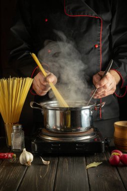 Deneyimli şef İtalyan makarnası hazırlar. Aşçı mutfakta spagetti tutuyor. Avrupa mutfağı