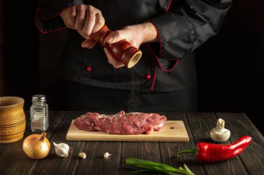 Şef sığır eti hazırlıyor ve biber ekliyor. Yemek hazırlarken mutfakta çalışma ortamı