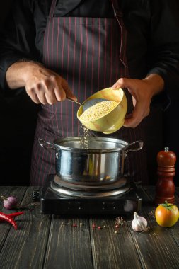 Şef kahvaltıda mısır ezmeli yulaf lapası pişirir. Bir restoranın ya da otelin mutfağında sağlıklı diyet yemekleri. Sağlıklı yemek tarifi.