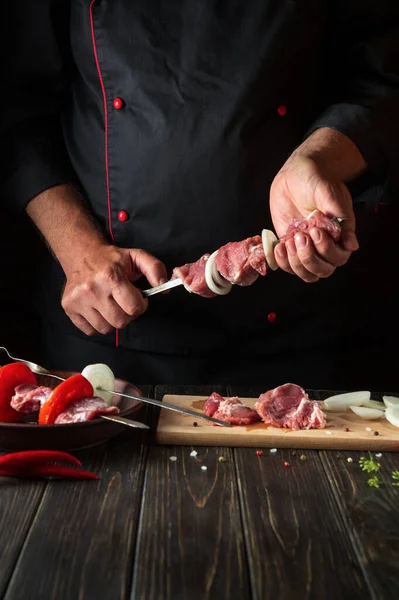 The chef prepares shish kebab from fresh sliced beef meat. Traditional oriental dish barbecue. Asian cuisine