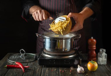The chef cooks soup with pasta and vegetables in a saucepan. Recipe for a delicious lunch for a restaurant or hotel
