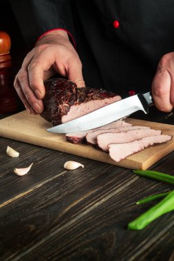 Cook hands slicing beef steak with knife on wood cutting board. Top view food preparation process concept