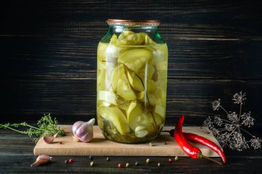 Canned vegetable marrow or zucchini in a jar with spices on a wooden board. Farm organic products. Free space for advertising