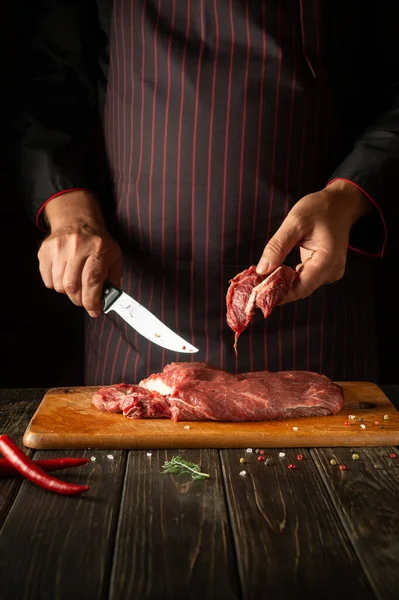 Cooking fresh beef by the chef hands in the kitchen. Recipe idea for a menu for a restaurant or hotel. Slicing raw meat.