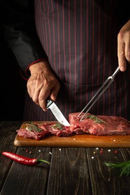 The chef prepares raw fresh beef meat for roasting or grilling. Recipe idea for hotel or restaurant. Working environment in the kitchen