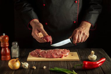 Professional cook cuts raw beef meat on a cutting board before baking. Asian cuisine. Hotel menu recipe idea