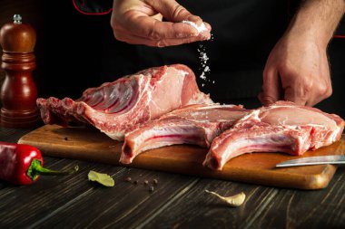 Experienced cook sprinkles raw ribs with salt. The concept of cooking delicious food for the hotel or restaurant
