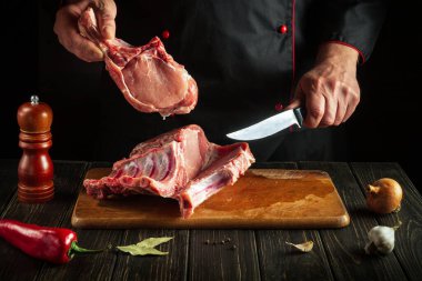 Cook cuts raw ribs on a cutting board before baking. Cooking delicious food in the kitchen
