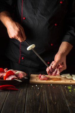 Chef pricks raw meat on a skewer. The process of cooking meat shish kebab in the kitchen by the hands of a cook
