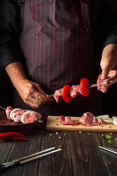 The chef prepares a delicious shish kebab with raw lamb in the kitchen. Asian cuisine.
