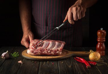 Preparing to grill meat steaks. Chef with a fork in his hand in the restaurant kitchen before cooking a delicious lunch.
