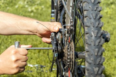 A mechanic repairs a bicycle chain on the street with a special key. Close-up of the master hands during urgent repairs bike.