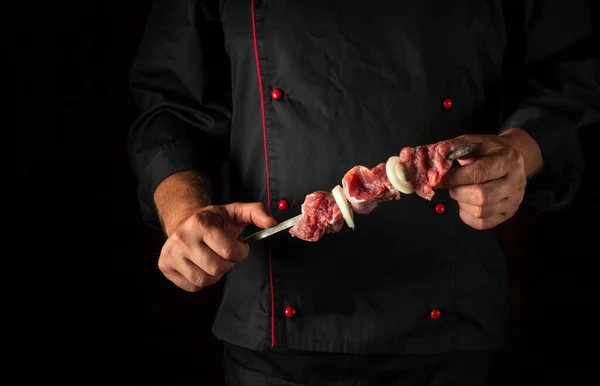 The chef holds shish kebab in hands with raw lamb meat. Asian national cuisine.