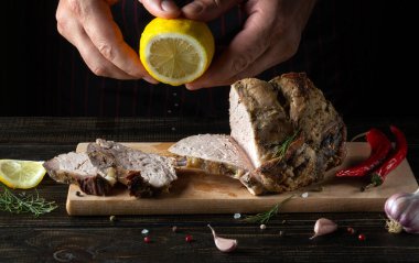 The chef adds fresh lemon juice to grilled meat. Space for advertisement or prescription on black background.