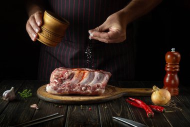 The cook sprinkles raw ribs with salt. The concept of cooking delicious food for the hotel or restaurant