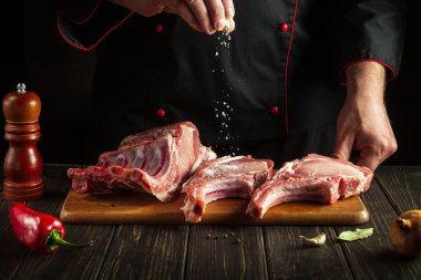 Profesyonel şef çiğ kaburga ve tuz serpiyor. Otel için lezzetli yemekler pişirme fikri.